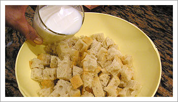 Taglia il pane a pezzi e disponilo in un recipiente con il latte.